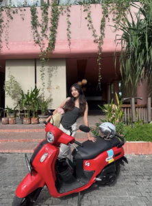 Wisatawan lokal berpose di samping skuter merah Fazzio dari Antara Rental di depan hotel, mencerminkan kemudahan sewa motor Bali dan layanan antar jemput dari sewa motor Bandara Bali yang praktis dan ramah wisatawan.