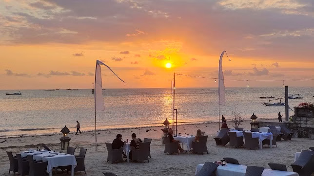 Tempat makan seafood murah Jimbaran dengan meja makan di tepi pantai sambil menikmati sunset.