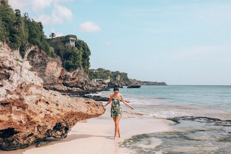 Traveler berjalan di atas batu karang di Pantai Tegal Wangi sambil menikmati keindahan laut lepas