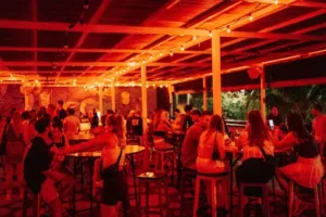 Suasana hiburan malam di dekat betu bolong beach, Bali, dengan bar yang ramai dipenuhi pengunjung yang menikmati minuman, musik, dan pencahayaan merah yang hangat.