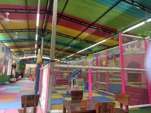 Area playground anak indoor di Big Garden Corner Bali dengan permainan warna-warni dan atap pelangi yang ceria.
