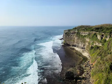 Tebing curam dengan pemandangan laut biru di sekitar Uluwatu Tample, Bali, menampilkan keindahan alam dan lokasi pura yang dramatis di pinggir Samudra Hindia.