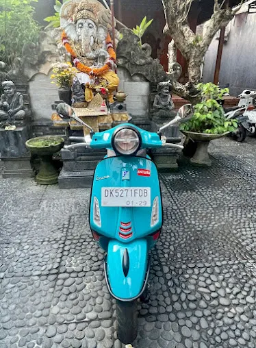 Motor vespa warna biru terparkir di depan patung Ganesha di Bali, bagian dari layanan sewa motor Bali untuk kebutuhan rental wisatawan.