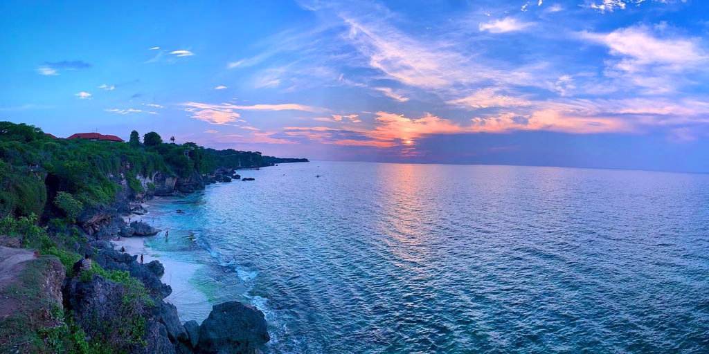 Pemandangan sunset indah di Tegal Wangi Beach, Jimbaran Bali dengan laut biru dan langit berwarna jingga